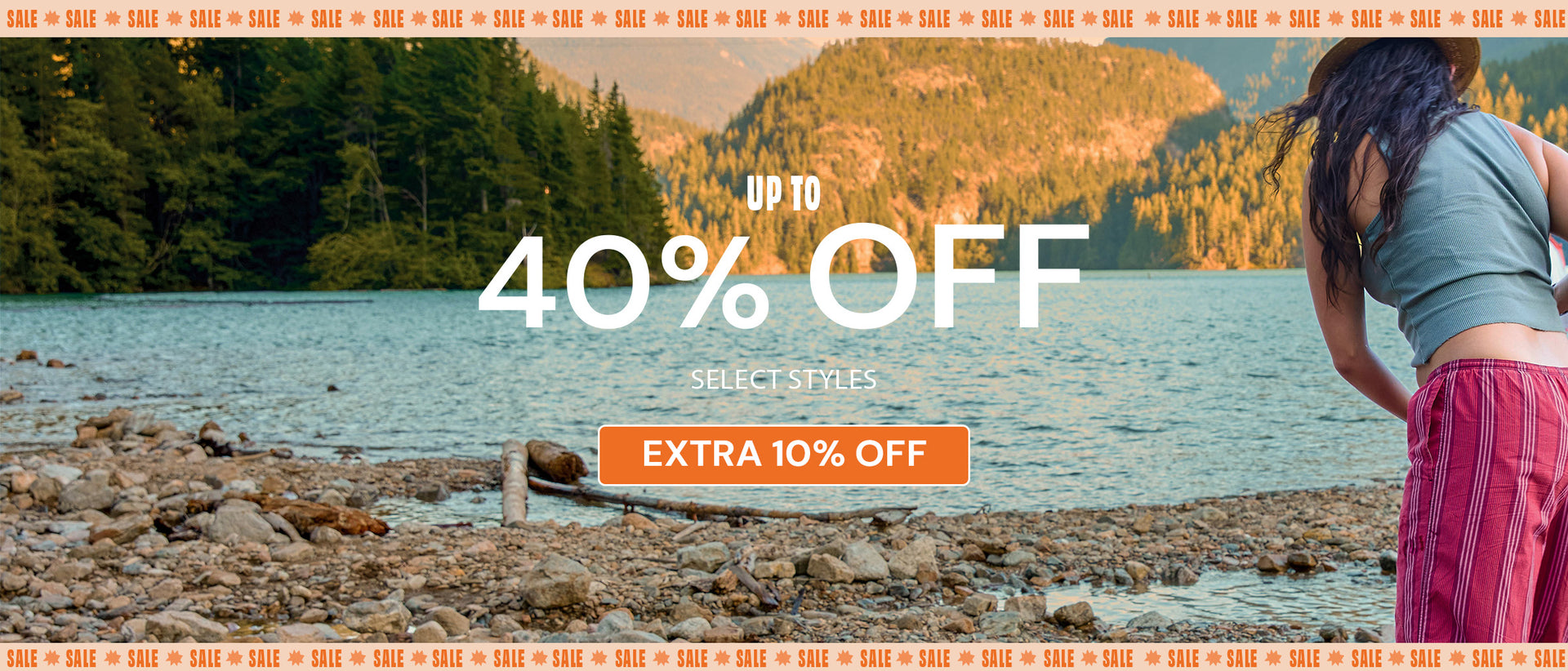 A JanSport promotional banner featuring a woman standing by a lake with mountains in the background, overlaid with large white text reading 'UP TO 40% OFF', a smaller 'SELECT STYLES' line, and an orange button that says 'EXTRA 10% OFF'.