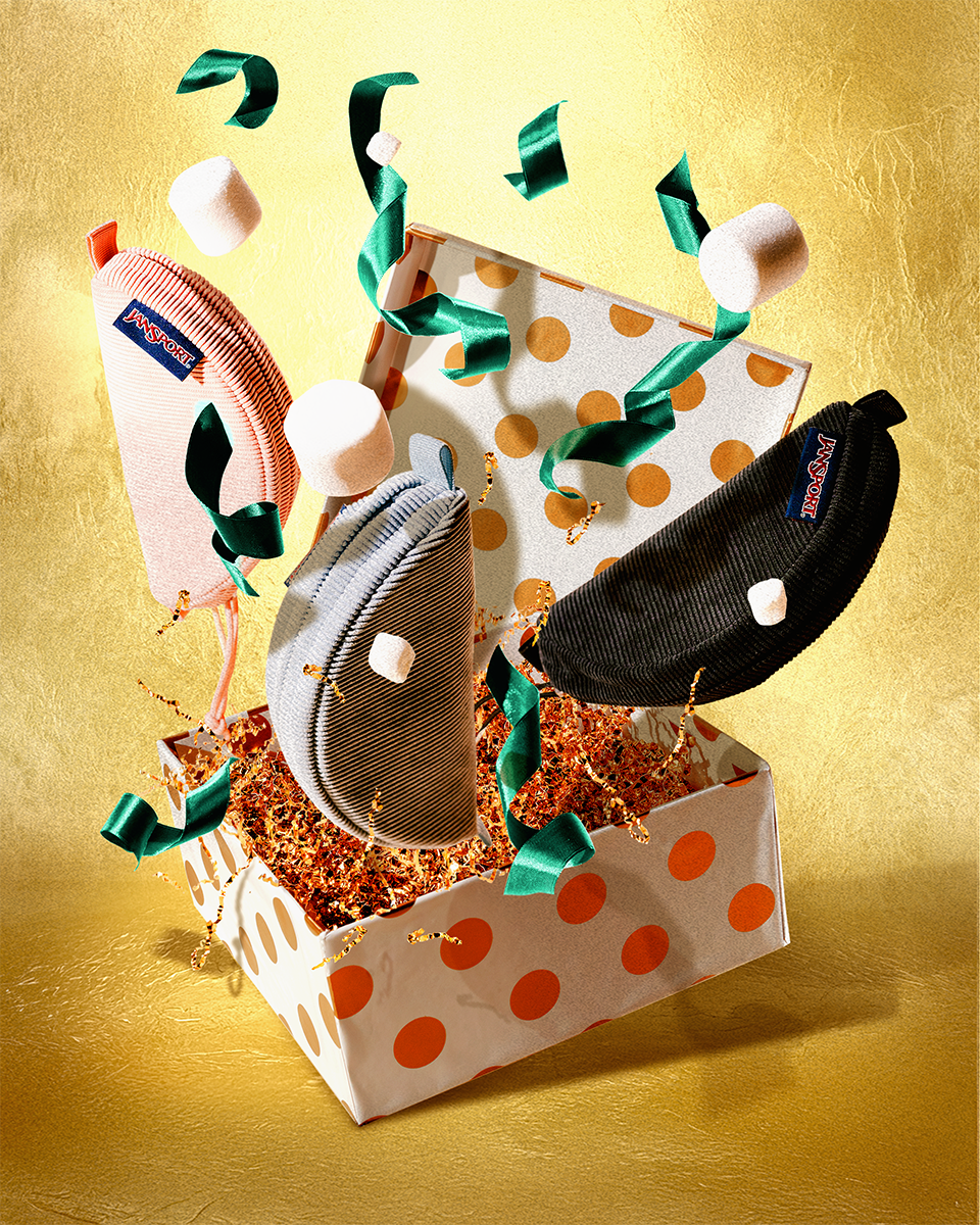 Three jansport Lunar pouches in a box with polka dot pattern on a gold background