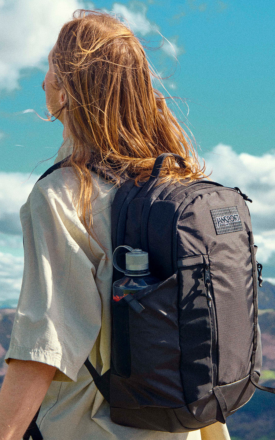 Person with a Jansport backpack against a scenic mountain backdrop